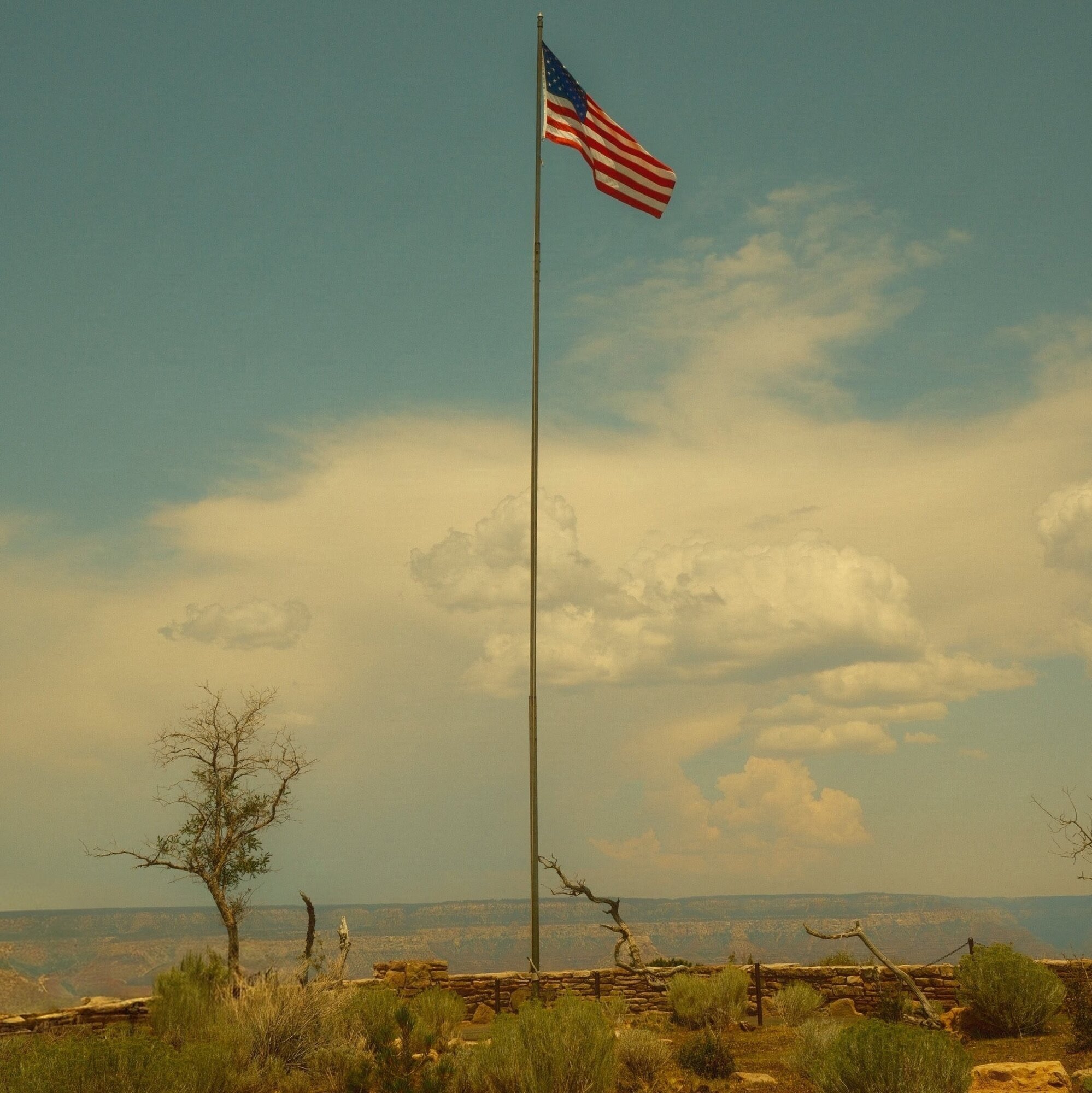 American flag over desert scrub at a hazy canyon overlook
