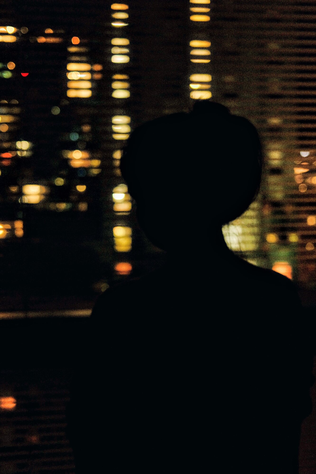 Dark silhouette against blurred amber city lights at night