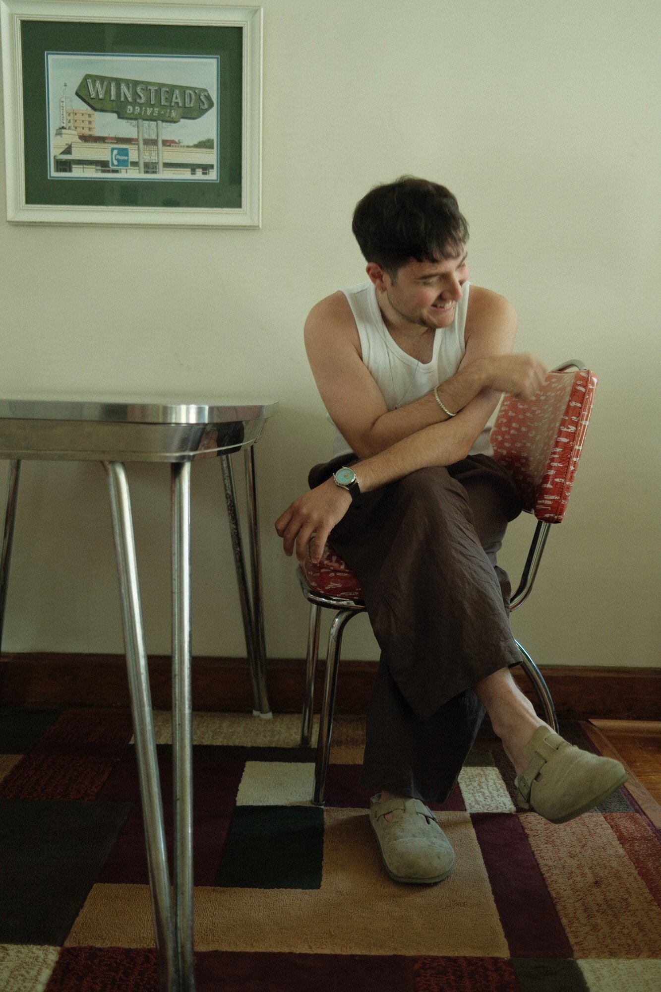 Man laughing on red vinyl dinette chair under Winstead's Drive-In print
